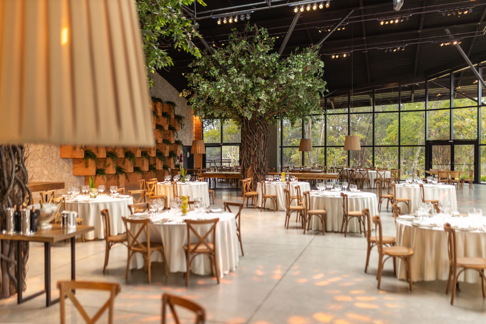 Spacious event hall featuring round tables, chairs, and indoor trees. Ideal for weddings or conferences. — Maximizing Your De